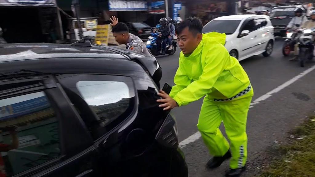 Polisi Bantu Dorong Mobil Pemudik yang Mogok di Simpang Tiga Sukamantri Ciawi Tasikmalaya